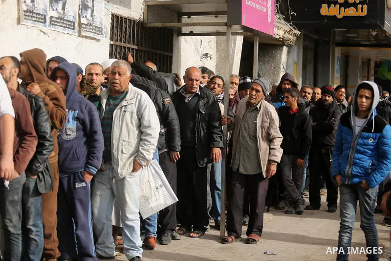 Palestinians of Social Affairs wait in front of Bank of Palestine to withdrew their financial aid in Gaza City on January 23, 2018. Photo by Ashraf Amra
