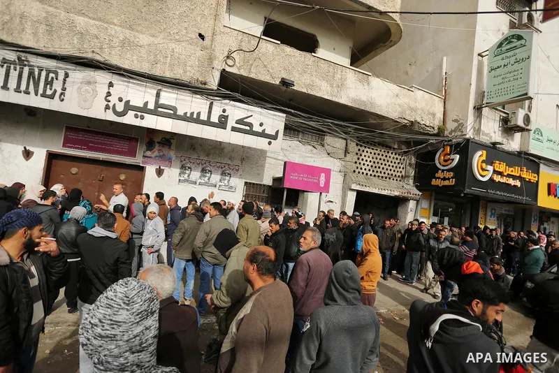 Palestinians of Social Affairs wait in front of Bank of Palestine to withdrew their financial aid in Gaza City on January 23, 2018. Photo by Ashraf Amra
