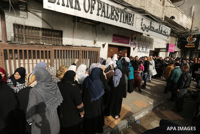 Palestinians of Social Affairs wait in front of Bank of Palestine to withdrew their financial aid in Gaza City on January 23, 2018. Photo by Ashraf Amra
