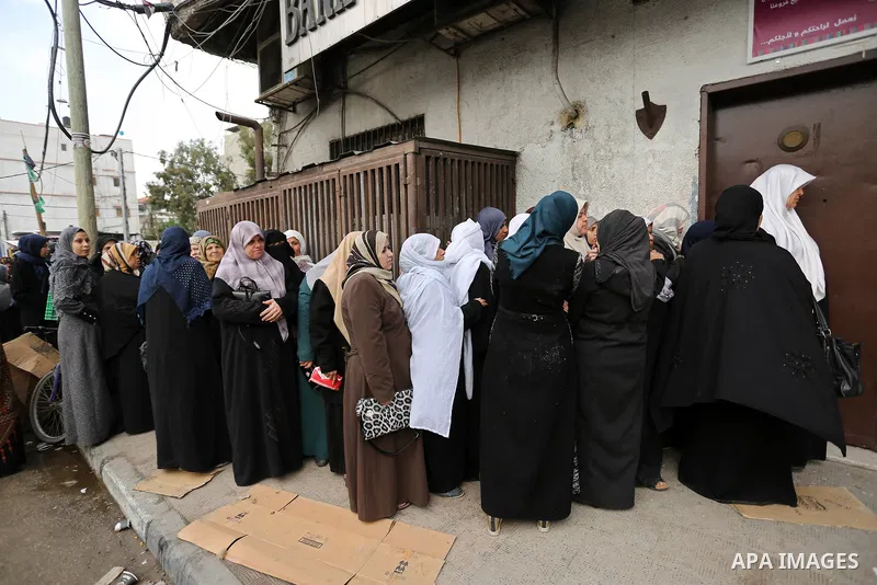 Palestinians of Social Affairs wait in front of Bank of Palestine to withdrew their financial aid in Gaza City on January 23, 2018. Photo by Ashraf Amra