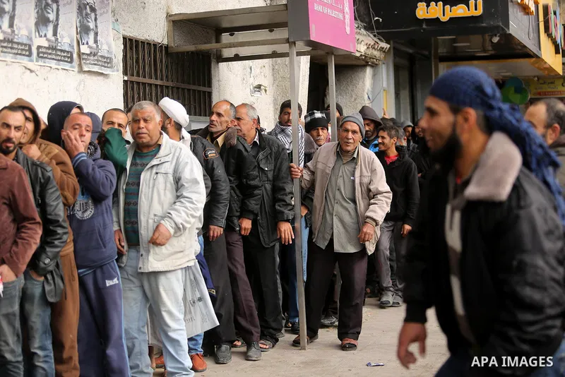 Palestinians of Social Affairs wait in front of Bank of Palestine to withdrew their financial aid in Gaza City on January 23, 2018. Photo by Ashraf Amra
