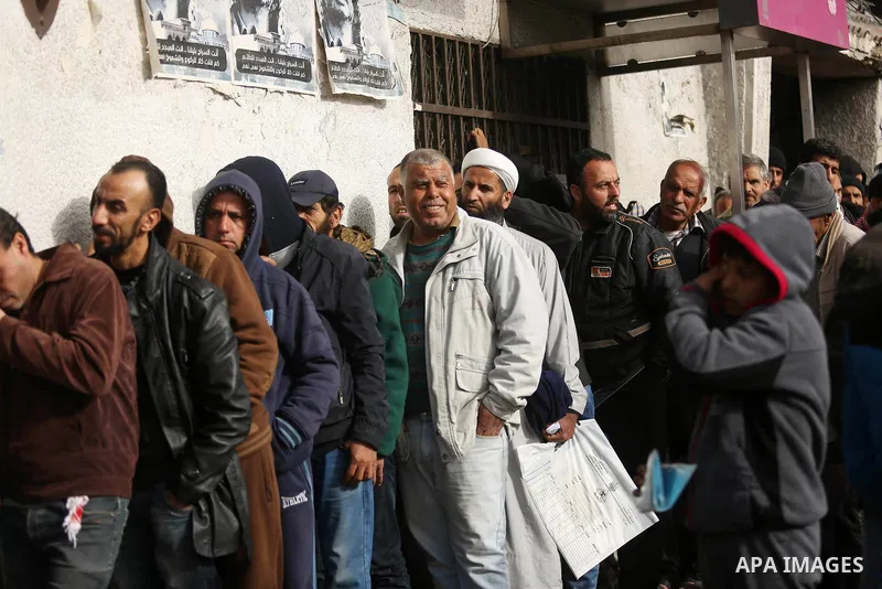 Palestinians of Social Affairs wait in front of Bank of Palestine to withdrew their financial aid in Gaza City on January 23, 2018. Photo by Ashraf Amra