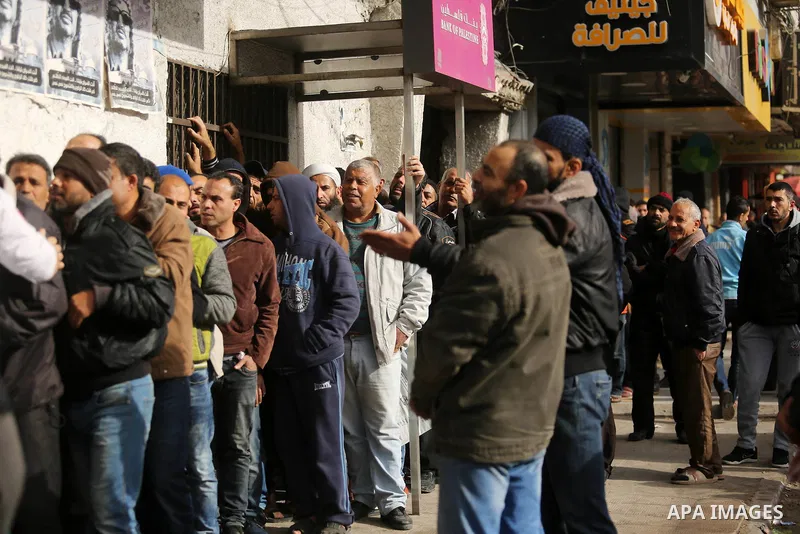 Palestinians of Social Affairs wait in front of Bank of Palestine to withdrew their financial aid in Gaza City on January 23, 2018. Photo by Ashraf Amra