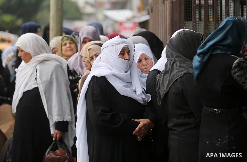 Palestinians of Social Affairs wait in front of Bank of Palestine to withdrew their financial aid in Gaza City on January 23, 2018. Photo by Ashraf Amra