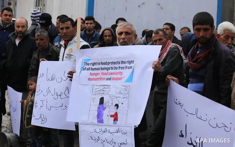 Palestinians hold banners during a protest against aid cut, in front of United Nations Development Programme office (UNDP), in Gaza City January 24, 2018. Photo by Mohammed Asad