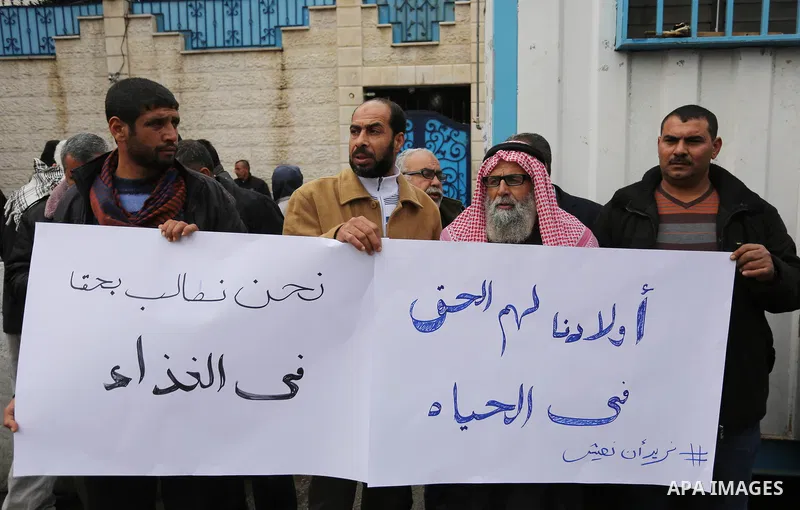 Palestinians hold banners during a protest against aid cut, in front of United Nations Development Programme office (UNDP), in Gaza City January 24, 2018. Photo by Ashraf Amra
