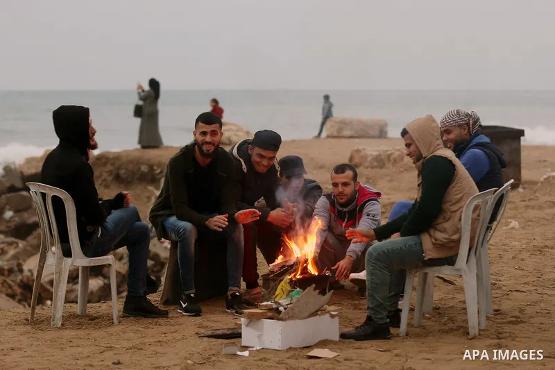Palestinians warm themselves on a cold day at the sea beach in Gaza City on January 24, 2018. Photo by Yasser Qudih