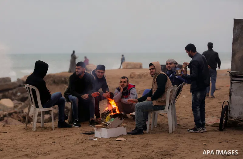 Palestinians warm themselves on a cold day at the sea beach in Gaza City on January 24, 2018. Photo by Yasser Qudih
