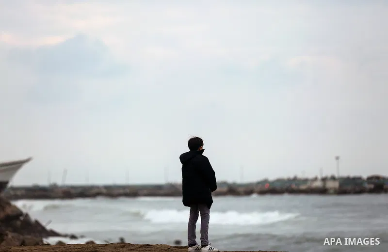 A Palestinian boy stands on a cold day at the sea beach in Gaza City on January 24, 2018. Photo by Yasser Qudih