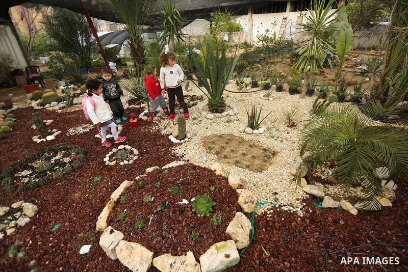 Palestinian girls look on the miniature cacti at the nursery in Jabalia in the northern Gaza Strip on January 25, 2018. Photo by Mohammed Asad