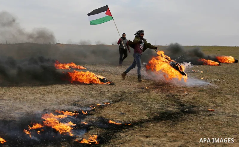 A Palestinian protester holds a fire and the Palestinian flag during clashes with Israeli security forces, as Palestinians call for 'a day of rage' against US President Donald Trump's decision to recognise Jerusalem as t...