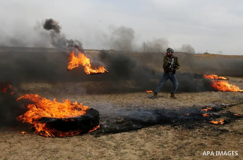 A Palestinian protester moves a burning tire during clashes with Israeli security forces, as Palestinians call for 'a day of rage' against US President Donald Trump's decision to recognise Jerusalem as the capital of Isr...