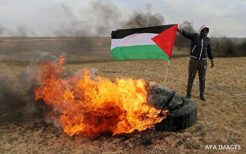 A Palestinian protester burns tires during clashes with Israeli security forces, as Palestinians call for 'a day of rage' against US President Donald Trump's decision to recognise Jerusalem as the capital of Israel, near...
