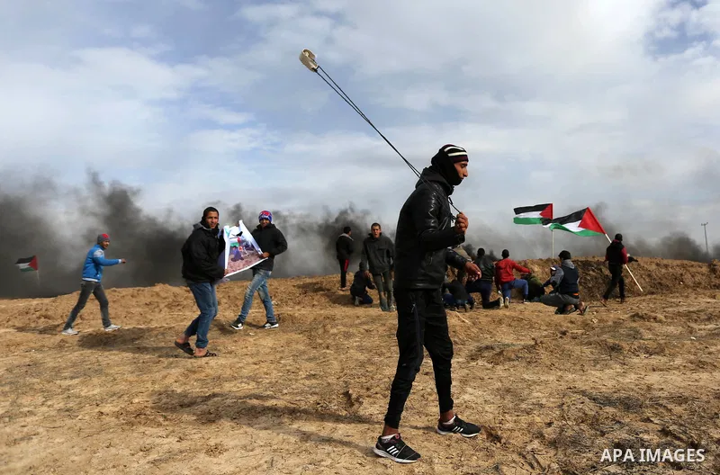 A Palestinian protester uses a slingshot to hurl stones towards Israeli security forces during clashes, as Palestinians call for 'a day of rage' against US President Donald Trump's decision to recognise Jerusalem as the...
