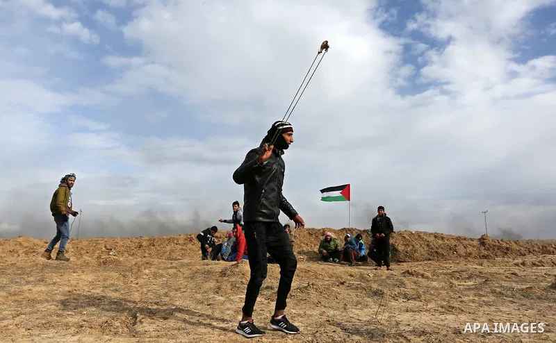 A Palestinian protester uses a slingshot to hurl stones towards Israeli security forces during clashes, as Palestinians call for 'a day of rage' against US President Donald Trump's decision to recognise Jerusalem as the...