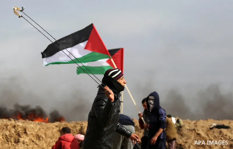 A Palestinian protester uses a slingshot to hurl stones towards Israeli security forces during clashes, as Palestinians call for 'a day of rage' against US President Donald Trump's decision to recognise Jerusalem as the...