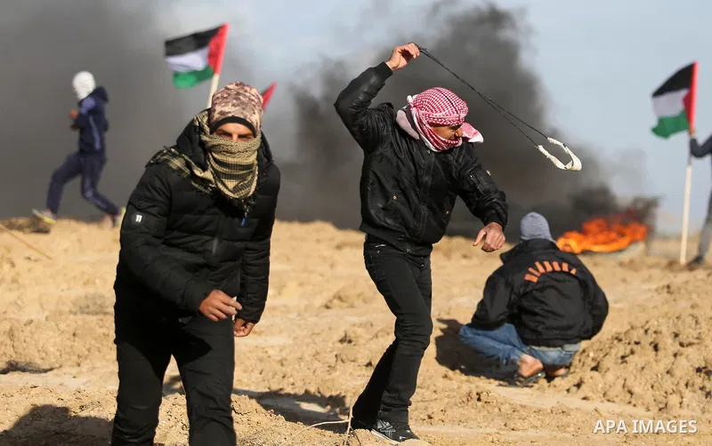 A Palestinian protester uses a slingshot to hurl stones towards Israeli security forces during clashes, as Palestinians call for 'a day of rage' against US President Donald Trump's decision to recognise Jerusalem as the...