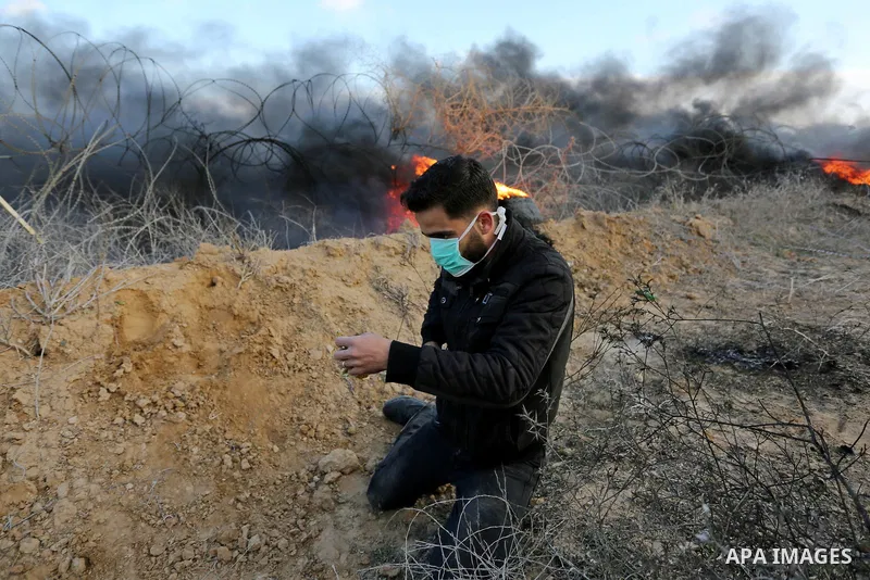 A Palestinian protester uses a slingshot to hurl stones towards Israeli security forces during clashes, as Palestinians call for 'a day of rage' against US President Donald Trump's decision to recognise Jerusalem as the...