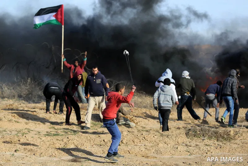 A Palestinian protester uses a slingshot to hurl stones towards Israeli security forces during clashes, as Palestinians call for 'a day of rage' against US President Donald Trump's decision to recognise Jerusalem as the...