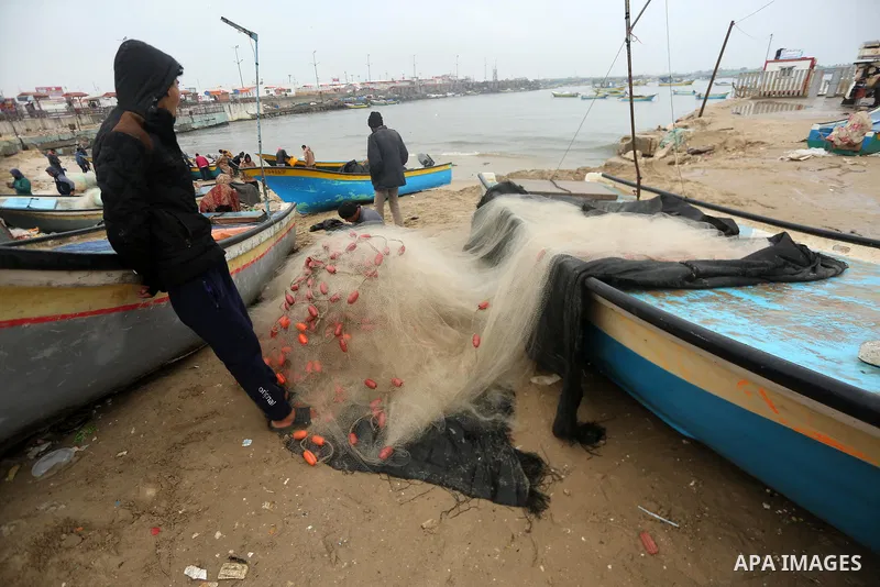 Palestinian fishermen work on their fishing boats on the sea port in Gaza City during a rainy storm on January 27, 2018. Photo by Mohammed Asad