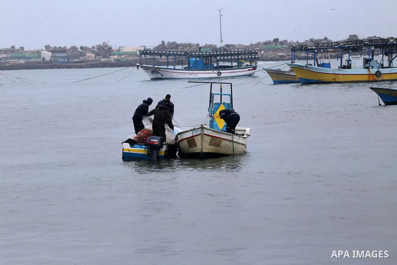 Palestinian fishermen work on their fishing boats on the sea port in Gaza City during a rainy storm on January 27, 2018. Photo by Mohammed Asad