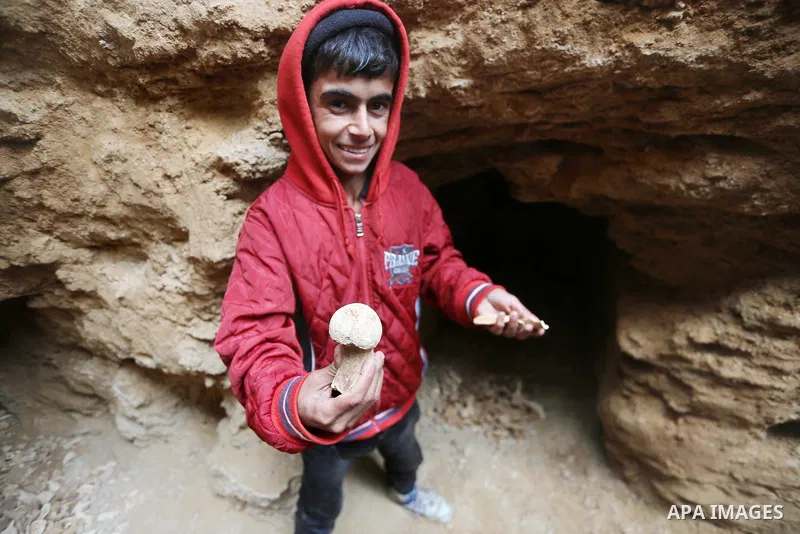 A Palestinian boy holds pottery fragments at a freshly-discovered cemetery which was found by Abdelkarim al-Kafarna in his backyard in town of Beit Hanoun, in the northern Gaza strip on January 27, 2018. Experts said the...