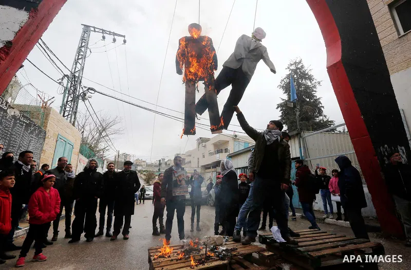 Palestinians hang a burning puppet bearing the portrait of US President Donald Trump, and his Vice President Mike Pence during a mock trial in the Aida refugee camp in the West Bank city of Bethlehem on January 27, 2018....