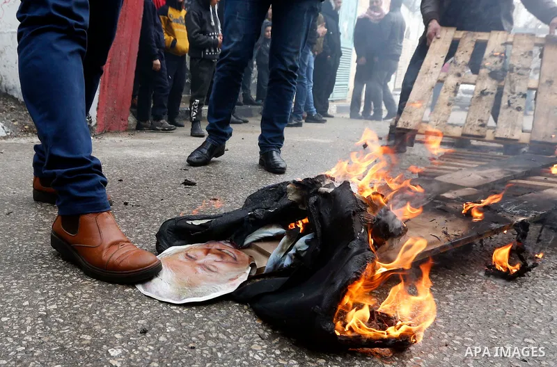 Palestinians step on an effigy of US President Donald Trump during a mock trial for him and Vice President Mike Pence, in the Aida refugee camp in the West Bank city of Bethlehem on January 27, 2018. Photo by Wisam Hashl...