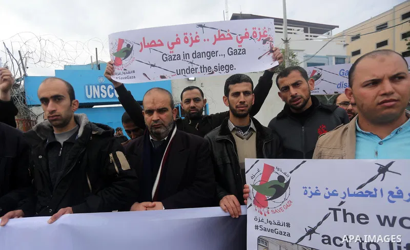 Palestinians hold banners during a protest against froze tens of millions of dollars in contributions to the United Nations Relief and Work Agency (UNRWA), and Israeli blockade on Gaza strip, in front of the headquarter...