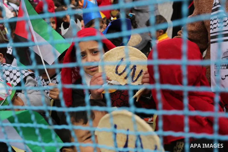 Palestinian children hold bread patties during a protest against aid cuts, outside the United Nations' offices in Khan Yunis in the southern Gaza Strip on January 28, 2018. On January 16, Washington held back $65 million...
