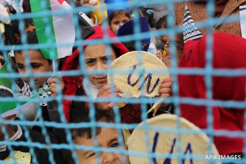Palestinian children hold bread patties during a protest against aid cuts, outside the United Nations' offices in Khan Yunis in the southern Gaza Strip on January 28, 2018. On January 16, Washington held back $65 million...