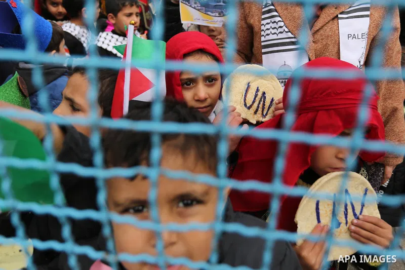 Palestinian children hold bread patties during a protest against aid cuts, outside the United Nations' offices in Khan Yunis in the southern Gaza Strip on January 28, 2018. On January 16, Washington held back $65 million...