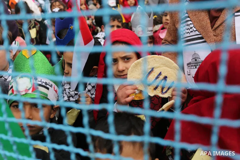 Palestinian children hold bread patties during a protest against aid cuts, outside the United Nations' offices in Khan Yunis in the southern Gaza Strip on January 28, 2018. On January 16, Washington held back $65 million...