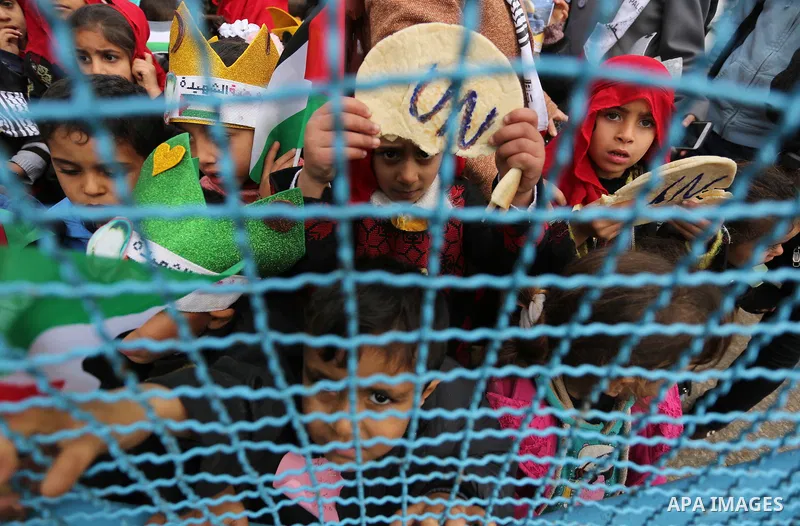Palestinian children hold bread patties during a protest against aid cuts, outside the United Nations' offices in Khan Yunis in the southern Gaza Strip on January 28, 2018. On January 16, Washington held back $65 million...