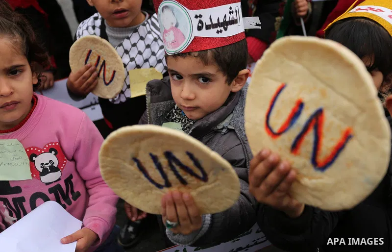 Palestinian children hold bread patties during a protest against aid cuts, outside the United Nations' offices in Khan Yunis in the southern Gaza Strip on January 28, 2018. On January 16, Washington held back $65 million...