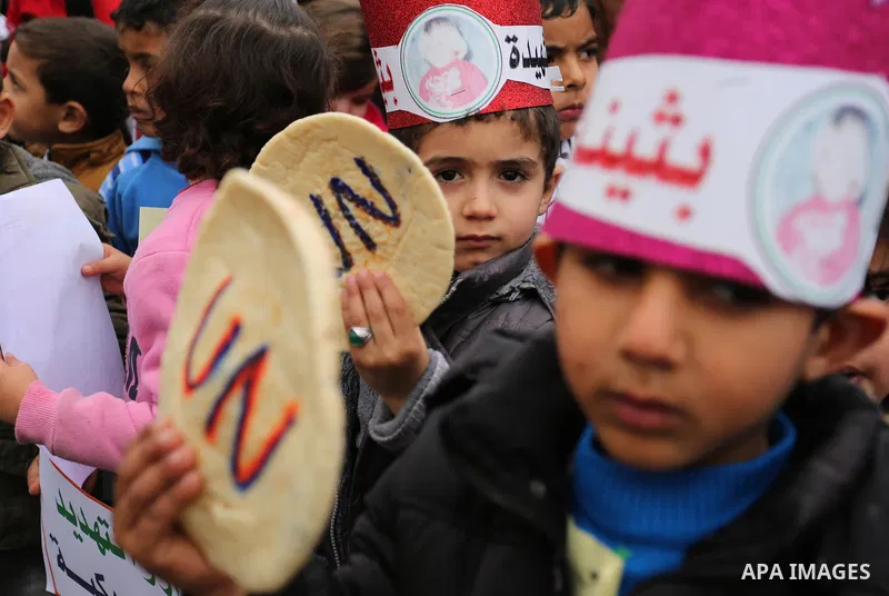 Palestinian children hold bread patties during a protest against aid cuts, outside the United Nations' offices in Khan Yunis in the southern Gaza Strip on January 28, 2018. On January 16, Washington held back $65 million...