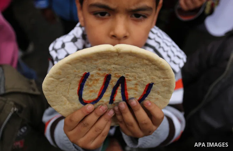 Palestinian children hold bread patties during a protest against aid cuts, outside the United Nations' offices in Khan Yunis in the southern Gaza Strip on January 28, 2018. On January 16, Washington held back $65 million...