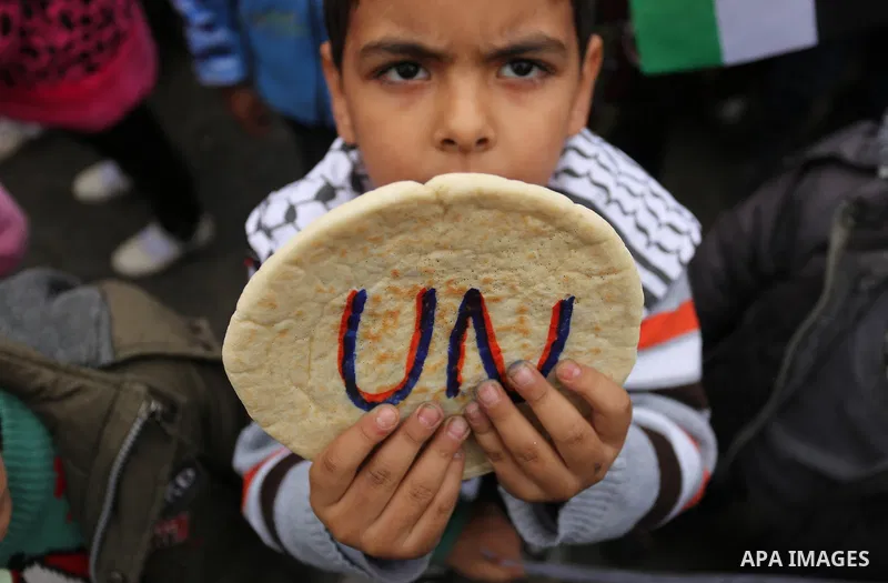 Palestinian children hold bread patties during a protest against aid cuts, outside the United Nations' offices in Khan Yunis in the southern Gaza Strip on January 28, 2018. On January 16, Washington held back $65 million...