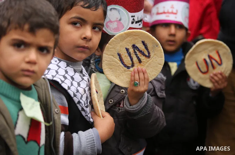 Palestinian children hold bread patties during a protest against aid cuts, outside the United Nations' offices in Khan Yunis in the southern Gaza Strip on January 28, 2018. On January 16, Washington held back $65 million...