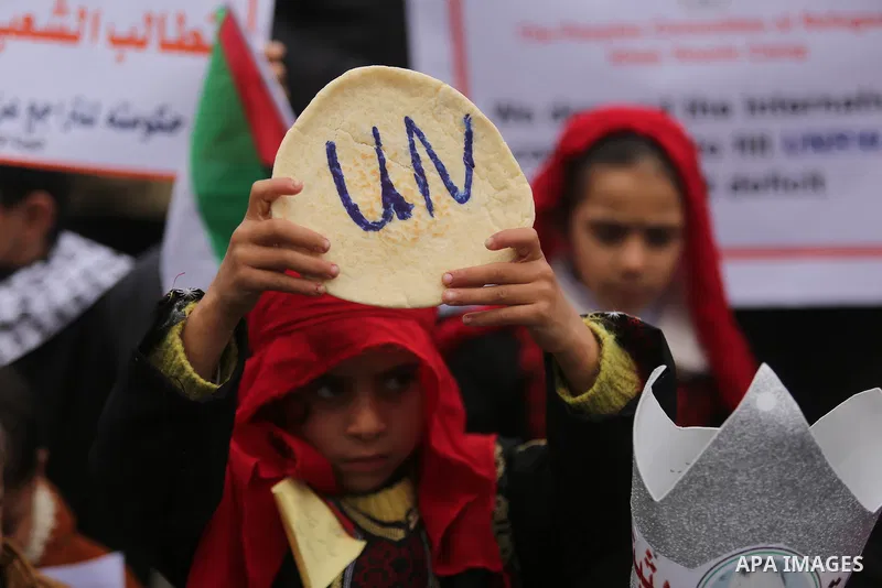 Palestinian children hold bread patties during a protest against aid cuts, outside the United Nations' offices in Khan Yunis in the southern Gaza Strip on January 28, 2018. On January 16, Washington held back $65 million...