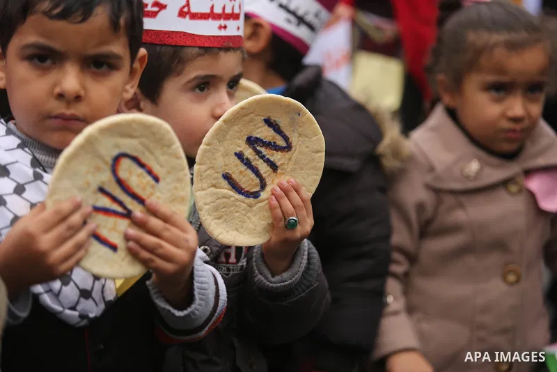 Palestinian children hold bread patties during a protest against aid cuts, outside the United Nations' offices in Khan Yunis in the southern Gaza Strip on January 28, 2018. On January 16, Washington held back $65 million...