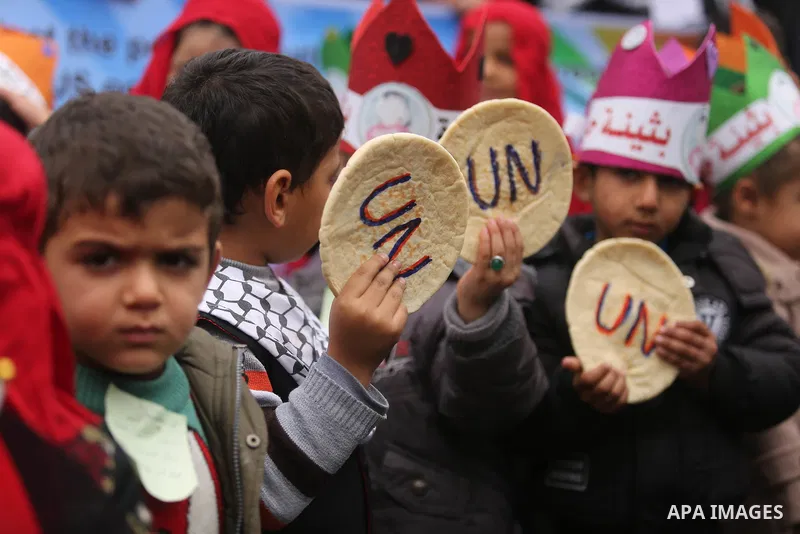 Palestinian children hold bread patties during a protest against aid cuts, outside the United Nations' offices in Khan Yunis in the southern Gaza Strip on January 28, 2018. On January 16, Washington held back $65 million...