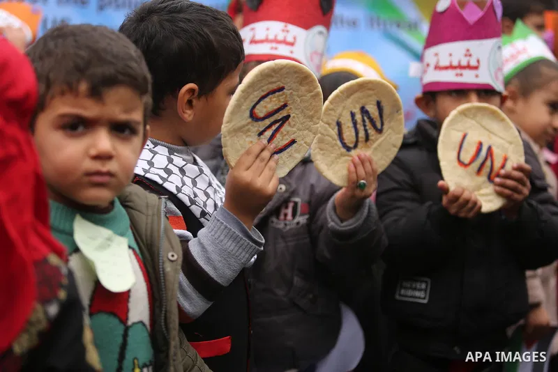 Palestinian children hold bread patties during a protest against aid cuts, outside the United Nations' offices in Khan Yunis in the southern Gaza Strip on January 28, 2018. On January 16, Washington held back $65 million...