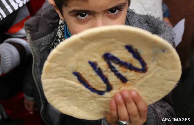 Palestinian children hold bread patties during a protest against aid cuts, outside the United Nations' offices in Khan Yunis in the southern Gaza Strip on January 28, 2018. On January 16, Washington held back $65 million...