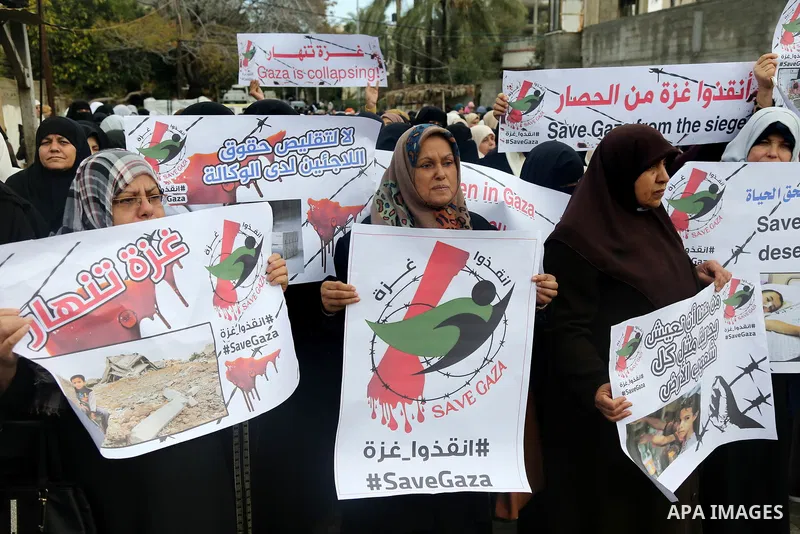 Palestinians hold banners during a protest against froze tens of millions of dollars in contributions to the United Nations Relief and Work Agency (UNRWA), and Israeli blockade on Gaza strip, in front of the headquarter...