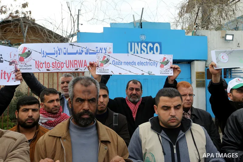Palestinians hold banners during a protest against froze tens of millions of dollars in contributions to the United Nations Relief and Work Agency (UNRWA), and Israeli blockade on Gaza strip, in front of the headquarter...