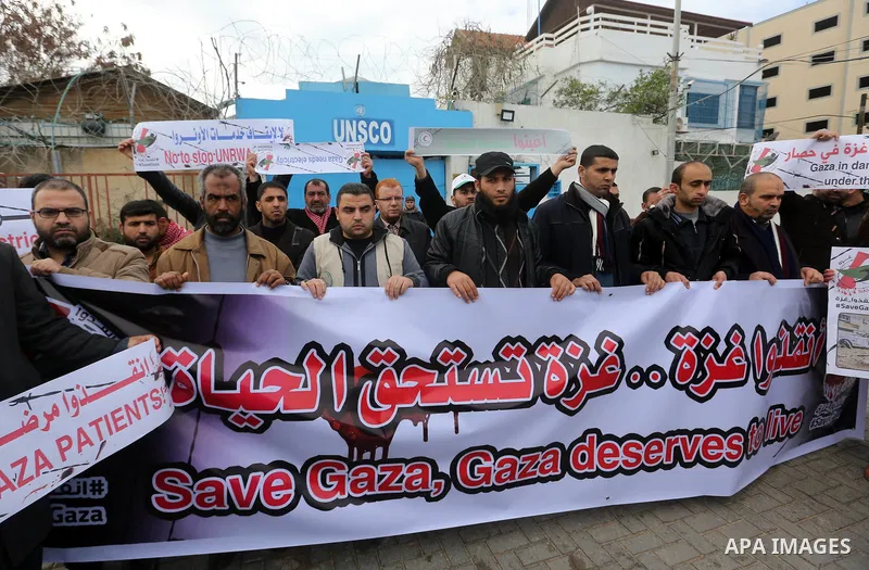 Palestinians hold banners during a protest against froze tens of millions of dollars in contributions to the United Nations Relief and Work Agency (UNRWA), and Israeli blockade on Gaza strip, in front of the headquarter...