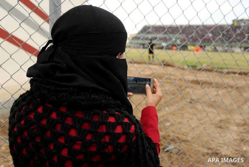 Palestinian women watch the football match between Al-Nuseirat and Al-Jalaa standing outside the fence of the stadium, at Nuseirat refugee camp, in the central of Gaza Strip, on January 28, 2018. Palestinian police allow...