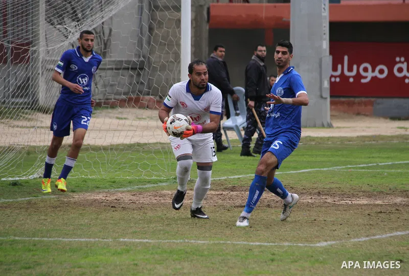 Palestinian players of Khadamat Rafah club (green) and Khadamat al-Shati (blue) compete during a football match at Palestine Stadium in Gaza city on January 28, 2018. Photo by Mahmoud Ajour