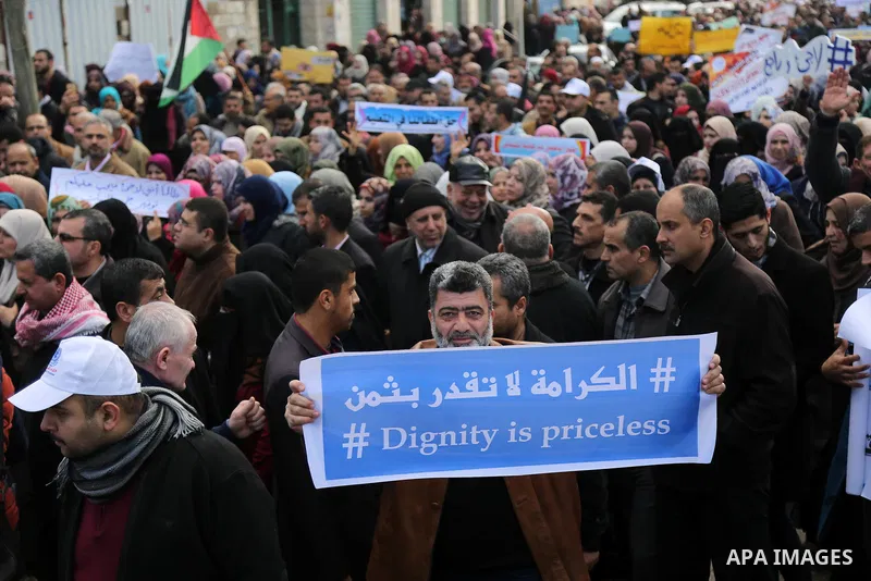 Palestinian employee of United Nations Relief and Works Agency (UNRWA) hold a sign during a protest against a U.S. decision to cut aid, in Gaza City January 29, 2018. Photo by Ashraf Amra